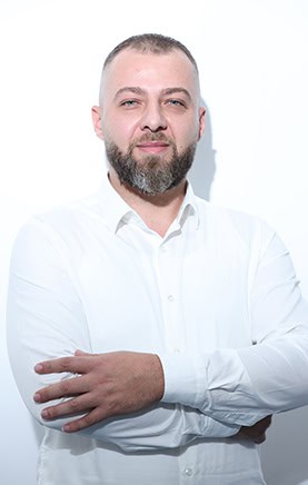 Dentista sorridente con braccia incrociate, in studio odontoiatrico, pronto ad aiutare i pazienti.