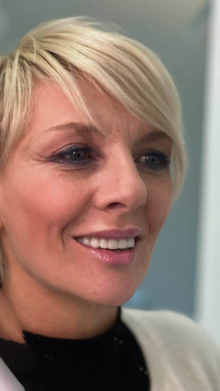 Dentista con sorriso amichevole durante una visita odontoiatrica.