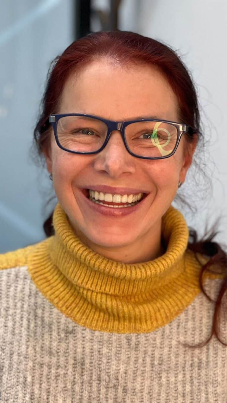 Sonrisa de mujer con gafas y jersey amarillo, feliz y amigable.