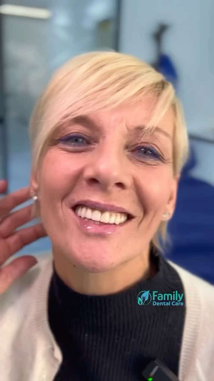 Sorridente donna con capelli biondi in studio dentistico, pronta per un trattamento odontoiatrico.