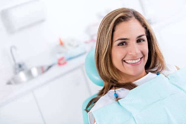 Donna sorridente in studio dentistico, pronta per il trattamento dentale.