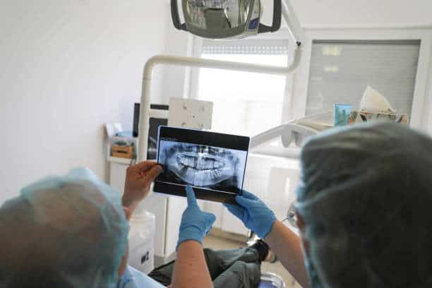 Immagine di un dentista che mostra un radiografia a un paziente durante una procedura di impianto de.