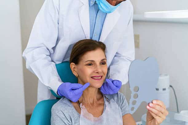 Donna sorridente in poltrona con denti nuovi.