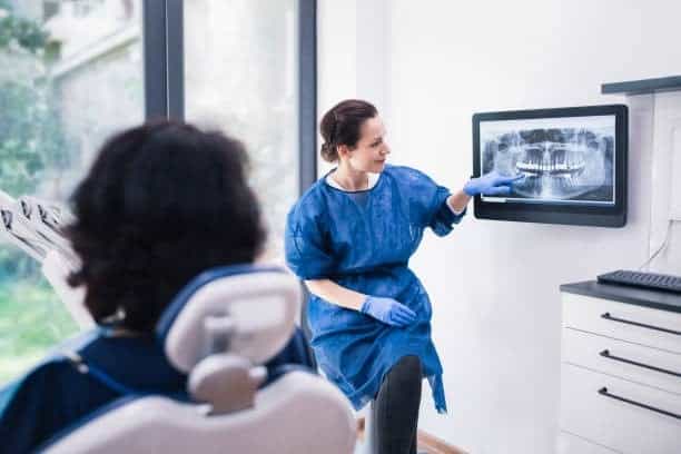 Immagine di un dentista che spiega un radiografia a un paziente in studio.