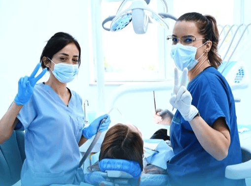 Due dentisti in sala operatoria odontoiatrica, indossano mascherine e guanti, mentre assistono un pa.
