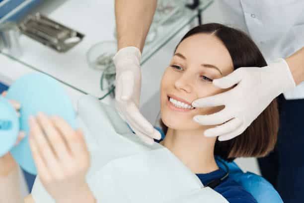 Donna sorridente durante una pulizia dentale dal dentista.