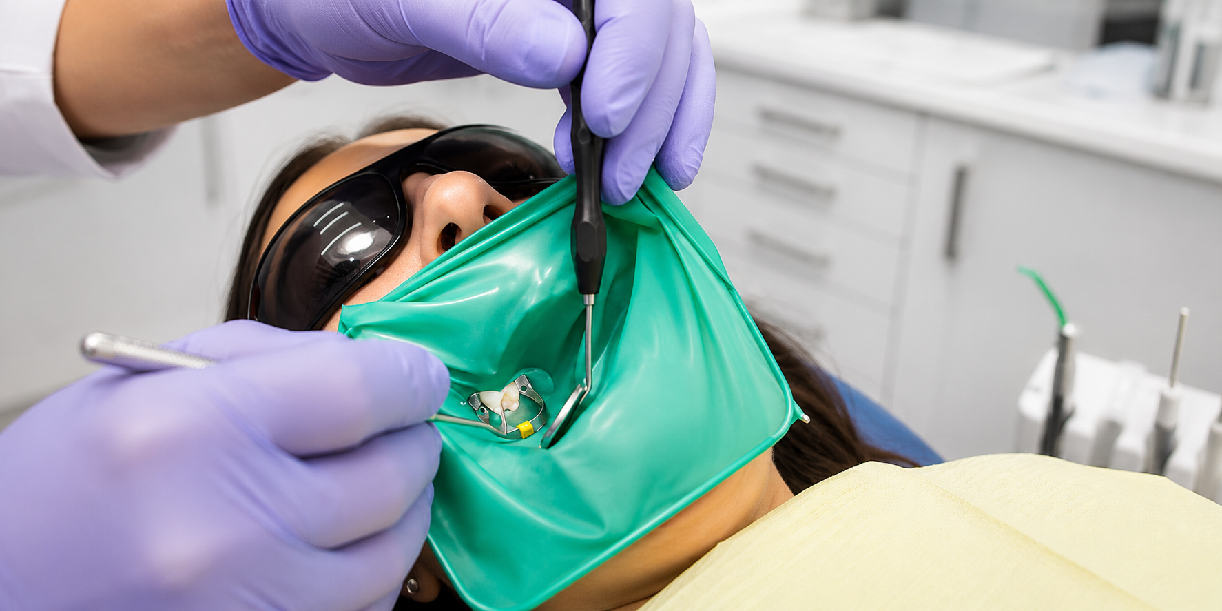Un dentiste effectue un traitement endodontique sur un patient avec une protection oculaire et un masque facial.