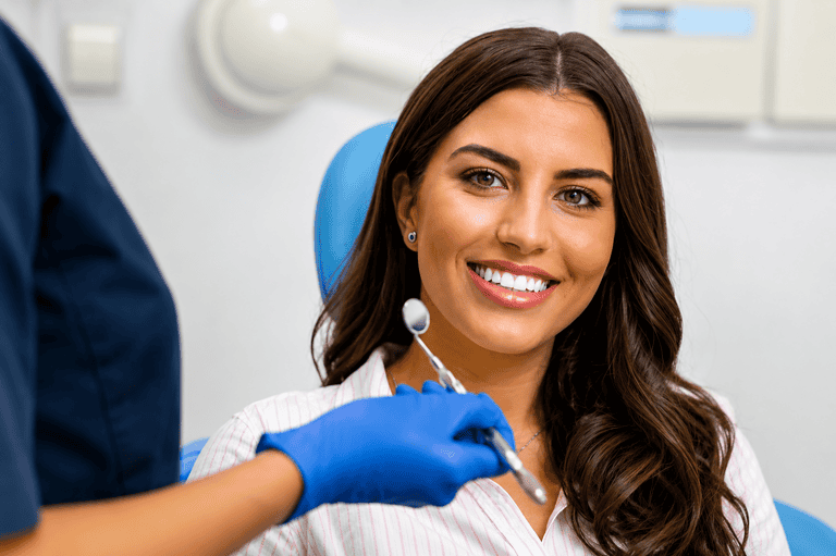 Donna sorridente in uno studio dentistico con un dentista che tiene uno strumento.