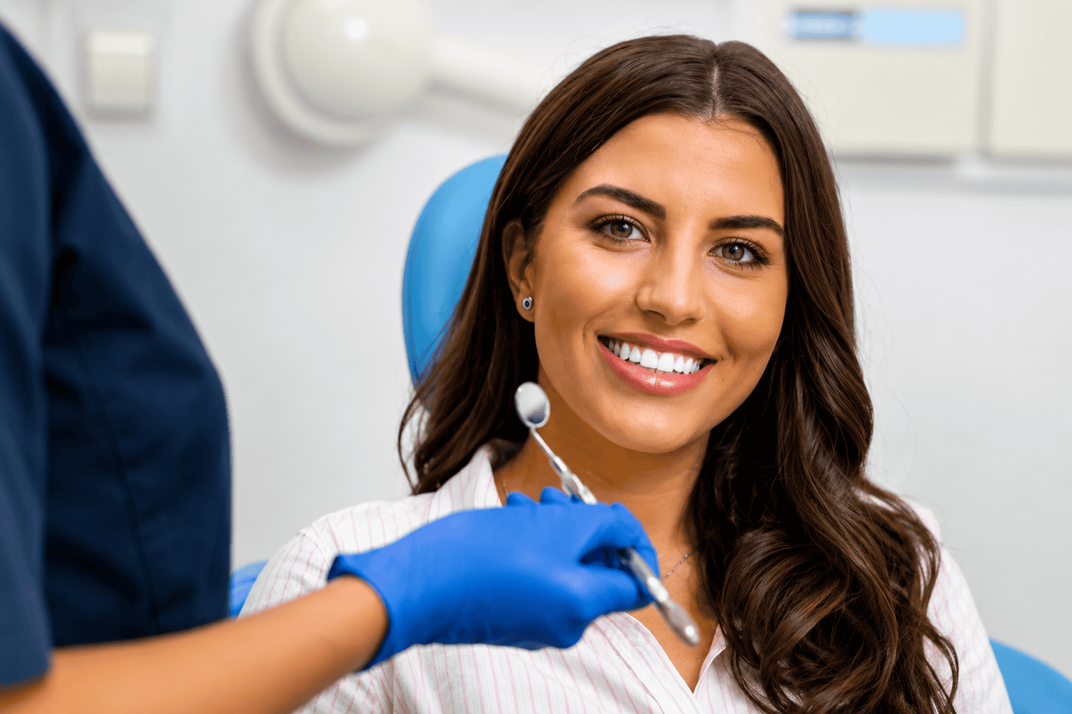 Donna sorridente in uno studio dentistico con un dentista che tiene uno strumento.