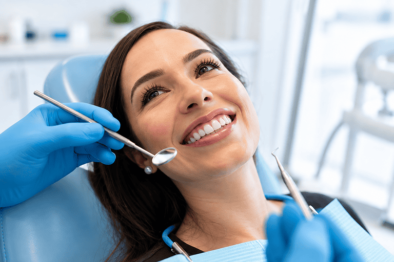 Dentista che esegue una cura dentale su una paziente sorridente.